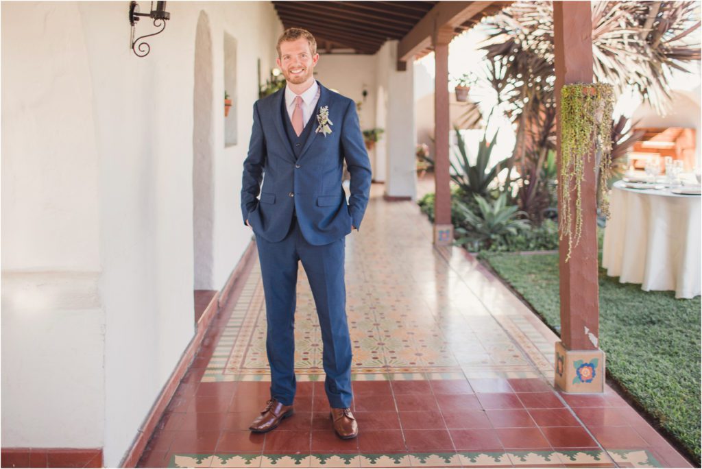A groom stands in a veranda at Casa Romantica on the day of his romantic cliffside wedding