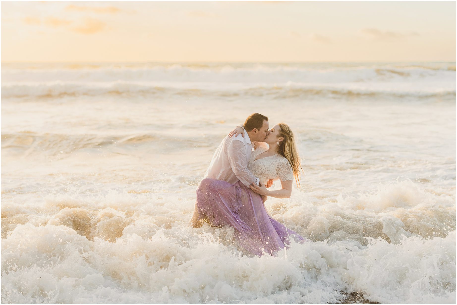 A couple kisses in the waves at RAT Beach in Torrance during Golden Hour