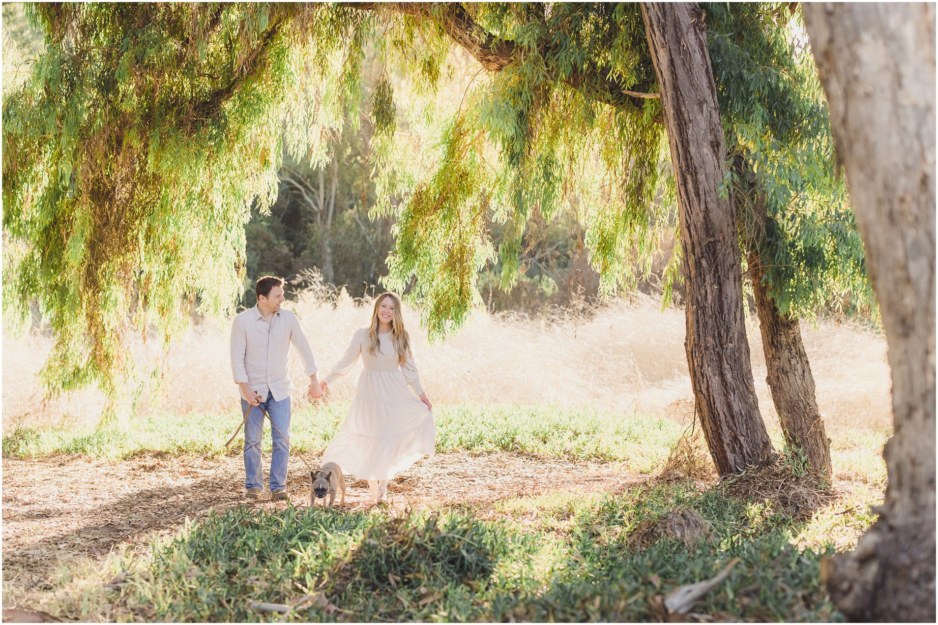 A couple walks near a tree in a field in Palos Verdes