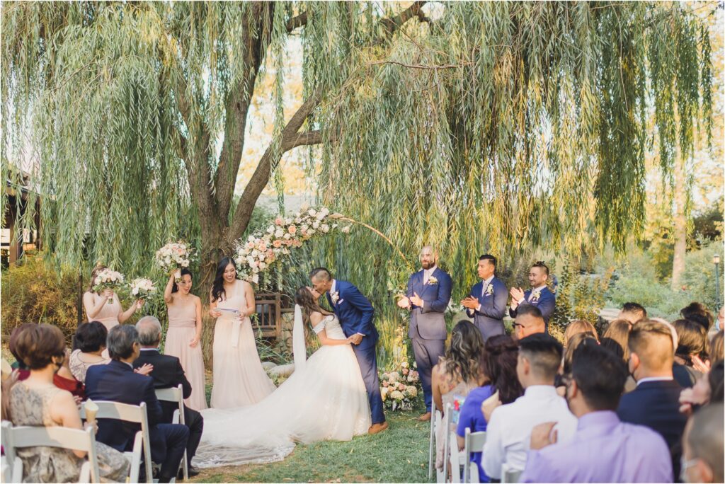 a bride and groom kiss under the willow tree in the rose garden during their Descanso Gardens wedding