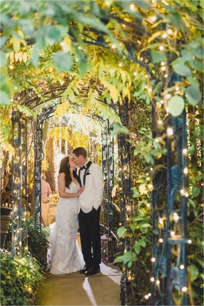 A bride and groom kiss under an arch at The Birchwood Room at Calamigos Ranch