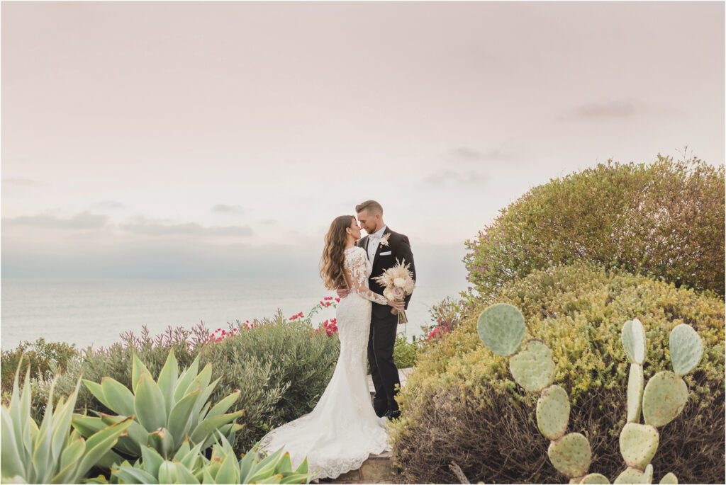 A bride and groom kiss amongst cactuses at Casa Romantic in San Clemente