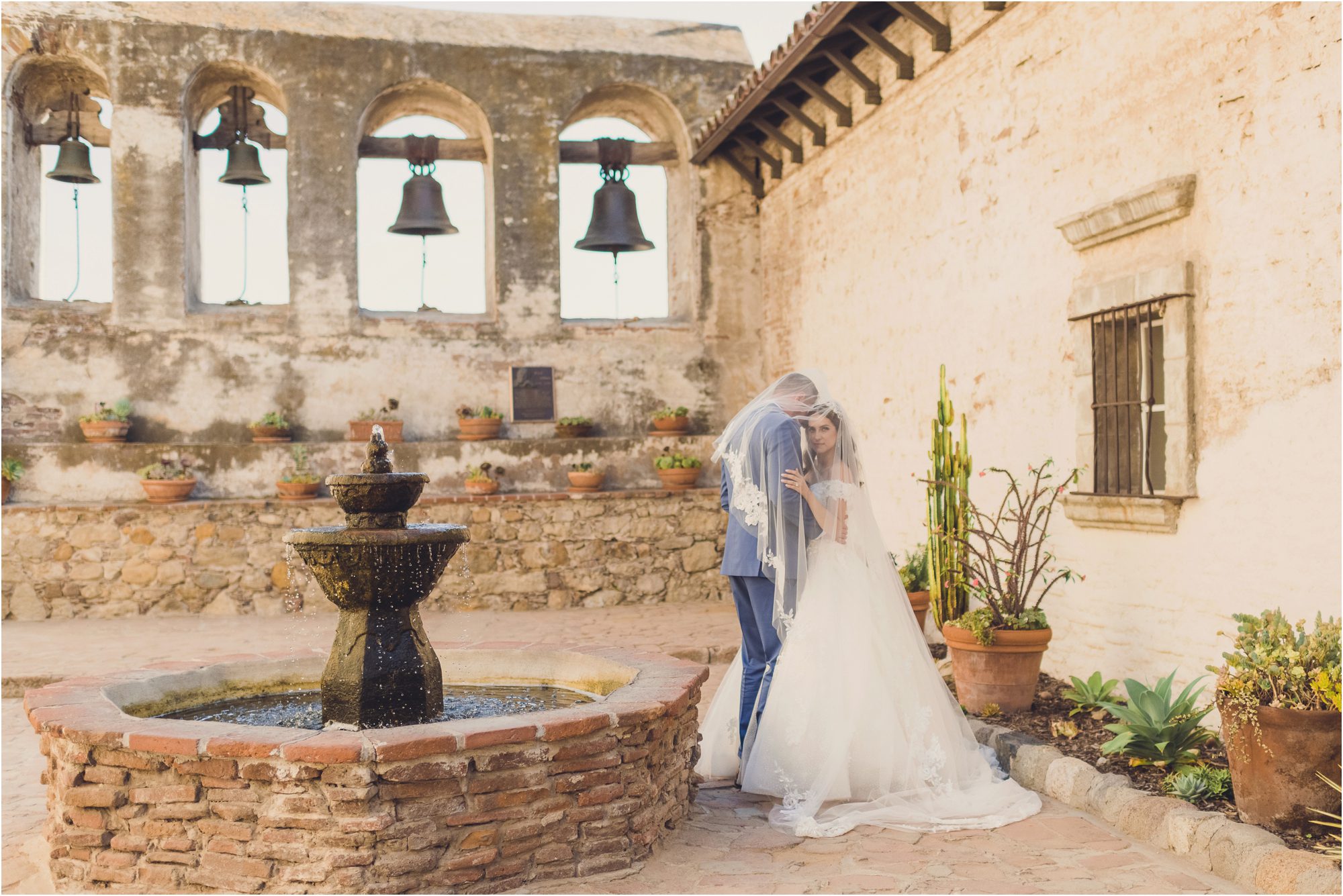 Dreamy San Juan Capistrano Wedding featuring a bide and groom posing for couples portraits near a fountain at the mission