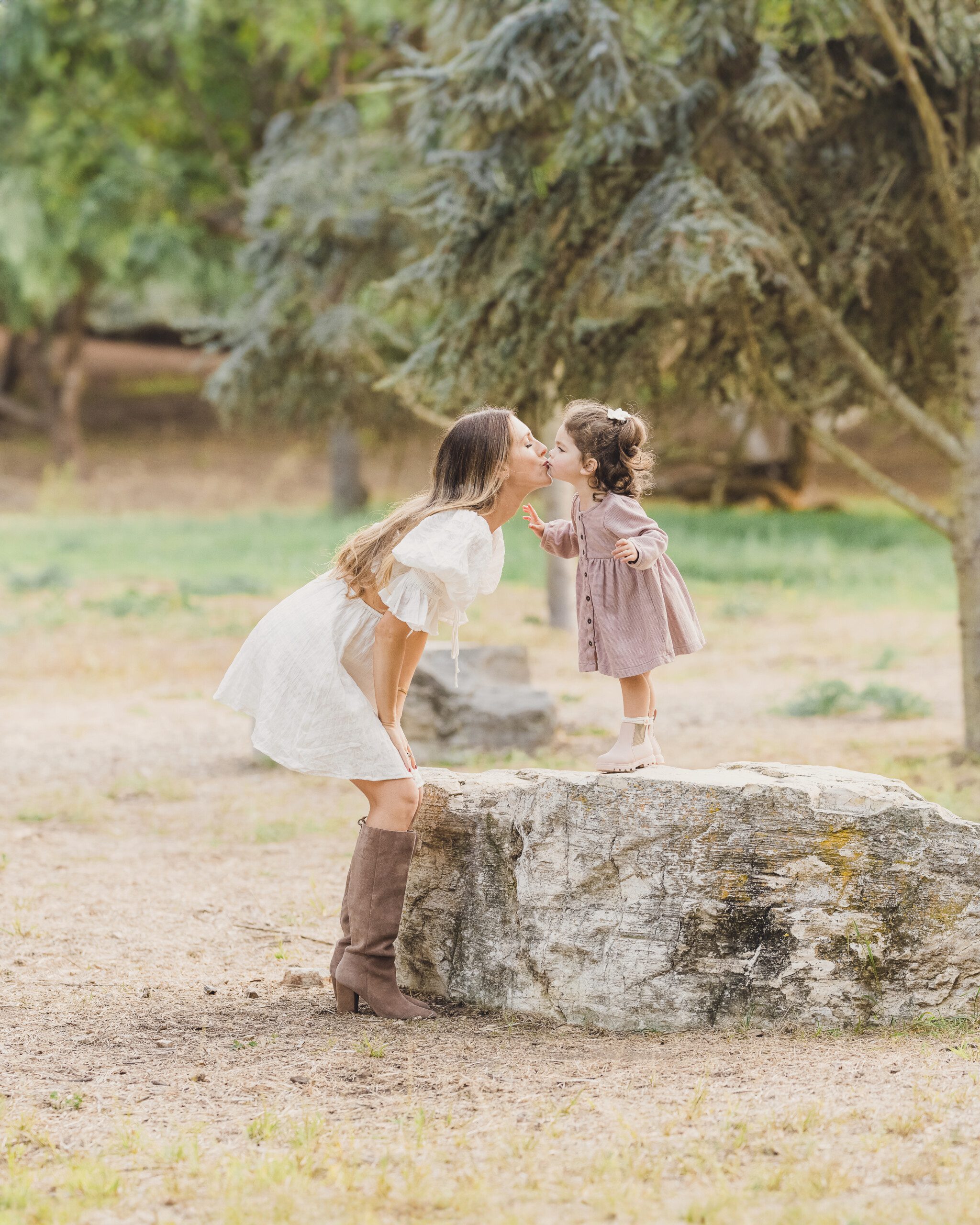 A mother and daughter share a kiss on a log