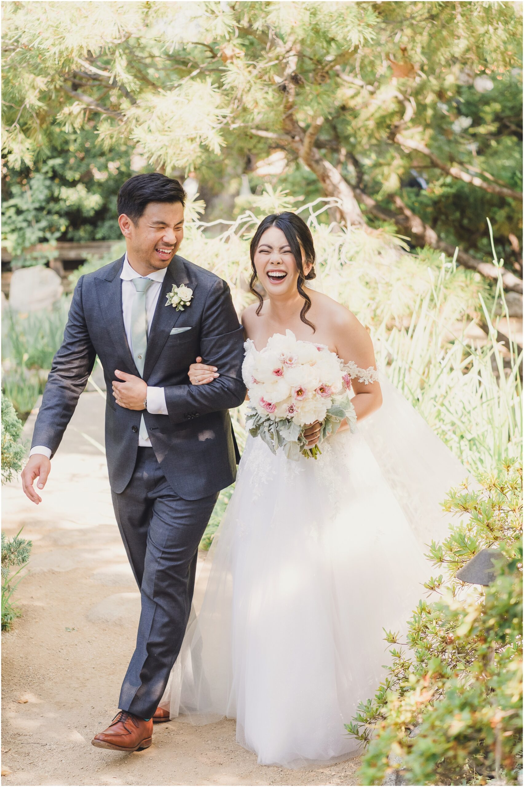 a bride and groom laugh and walk through a path in sorrier stearns Japanese Gardens