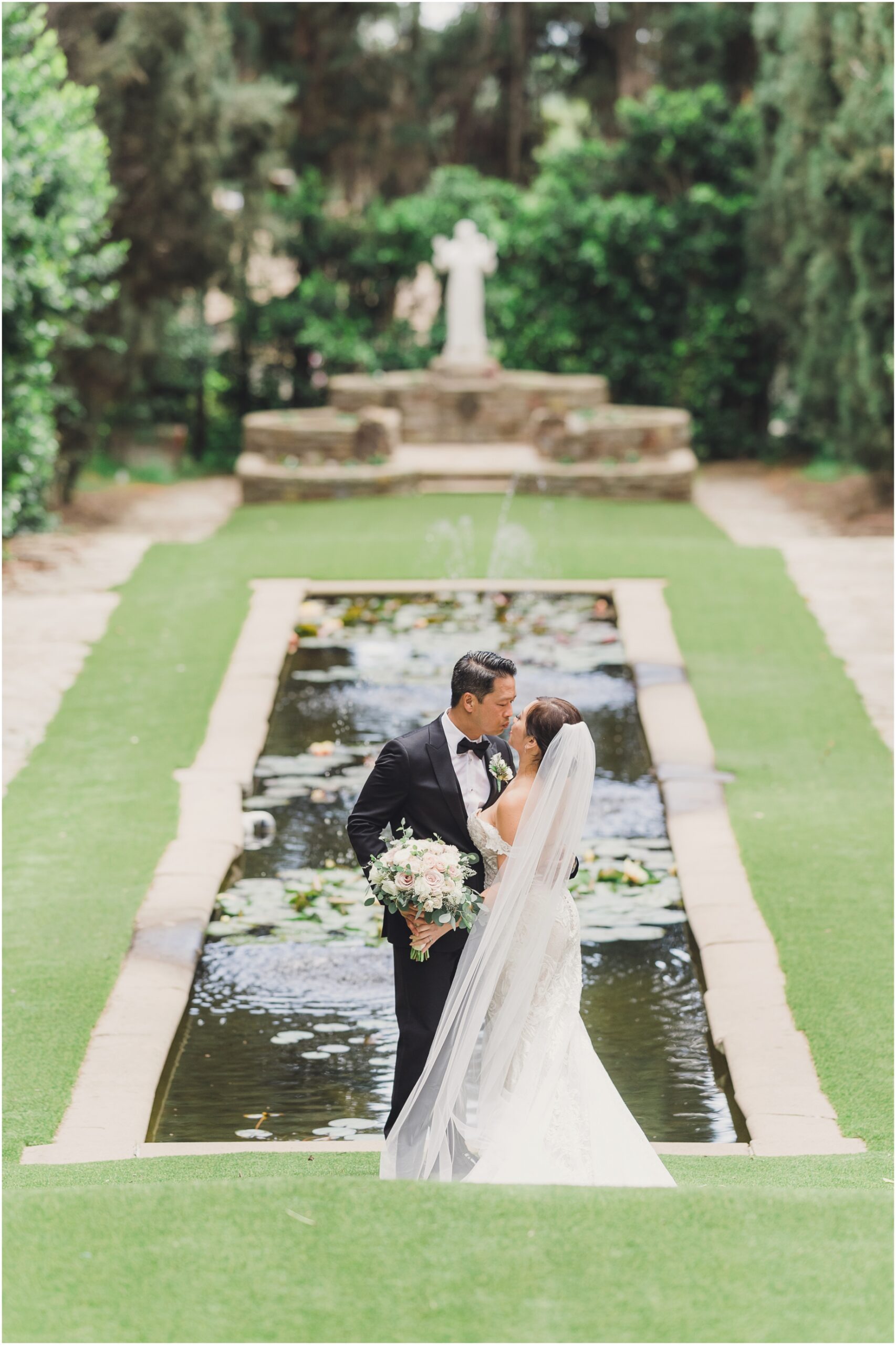 A kiss is shared in front of a beautiful pond at Villa del Sol d'Oro