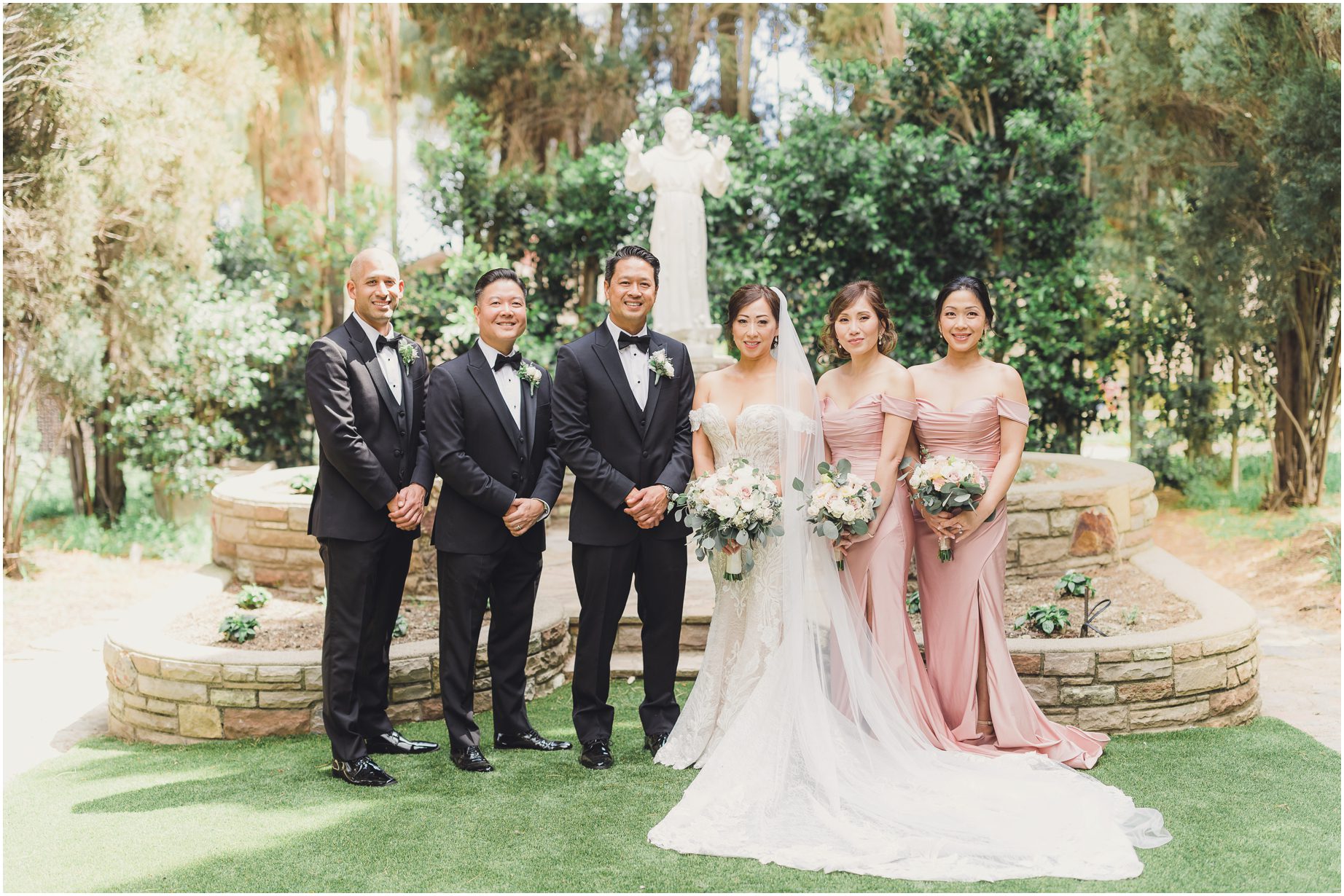 During a wedding at Villa del sol d'Oro, the bridal party poses for a traditional portrait in front of the statue of St Francis.