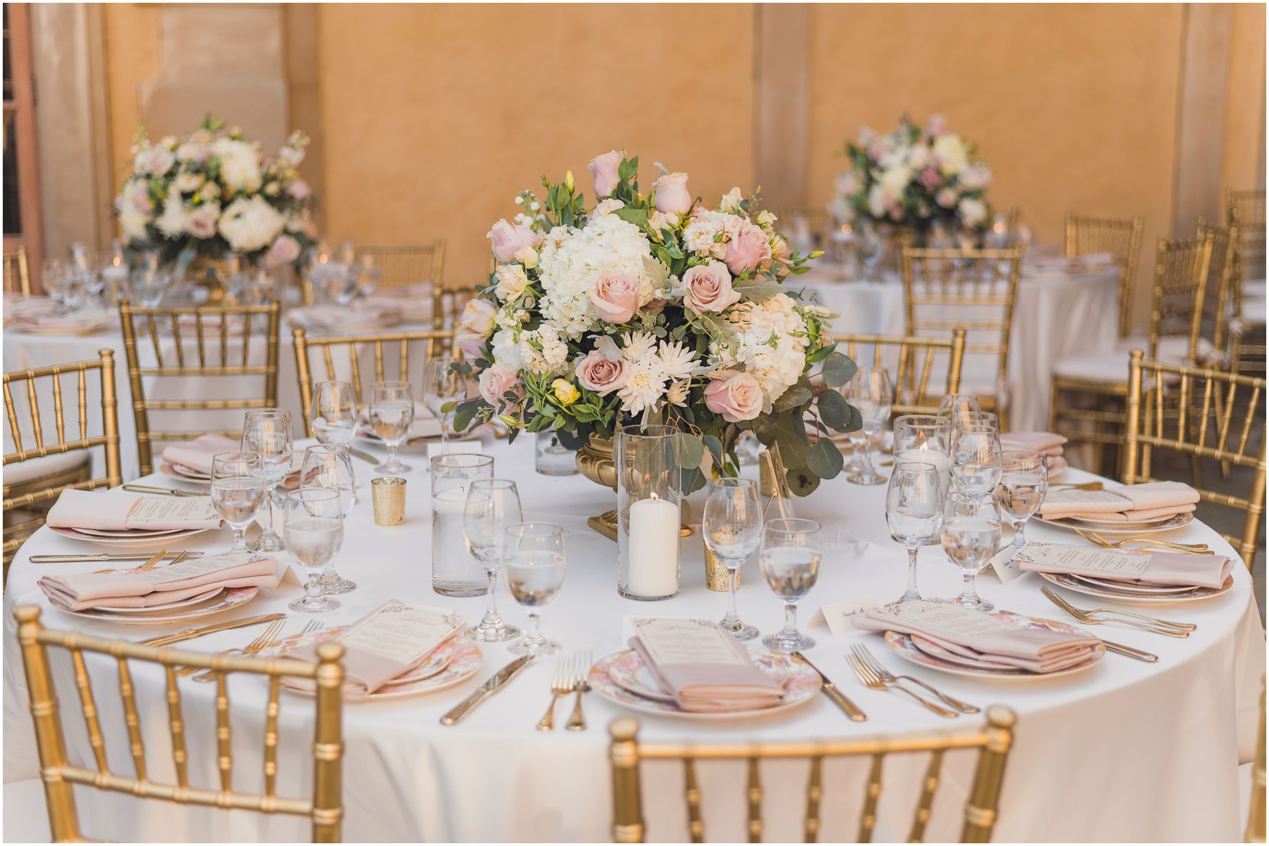 Table setup for a whimsical wedding at Villa del sol d'Oro featuring pink roses, white hydrangeas, and daisies.