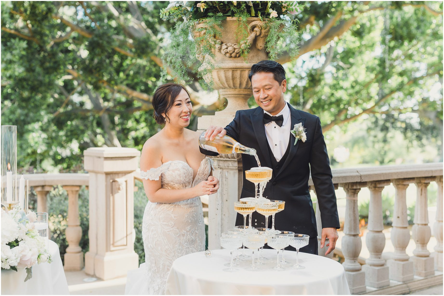A bride and groom pose in front of their dreamy wedding details on their wedding day at Villa del sol D'oro. Featuring a champagne tower and flowers