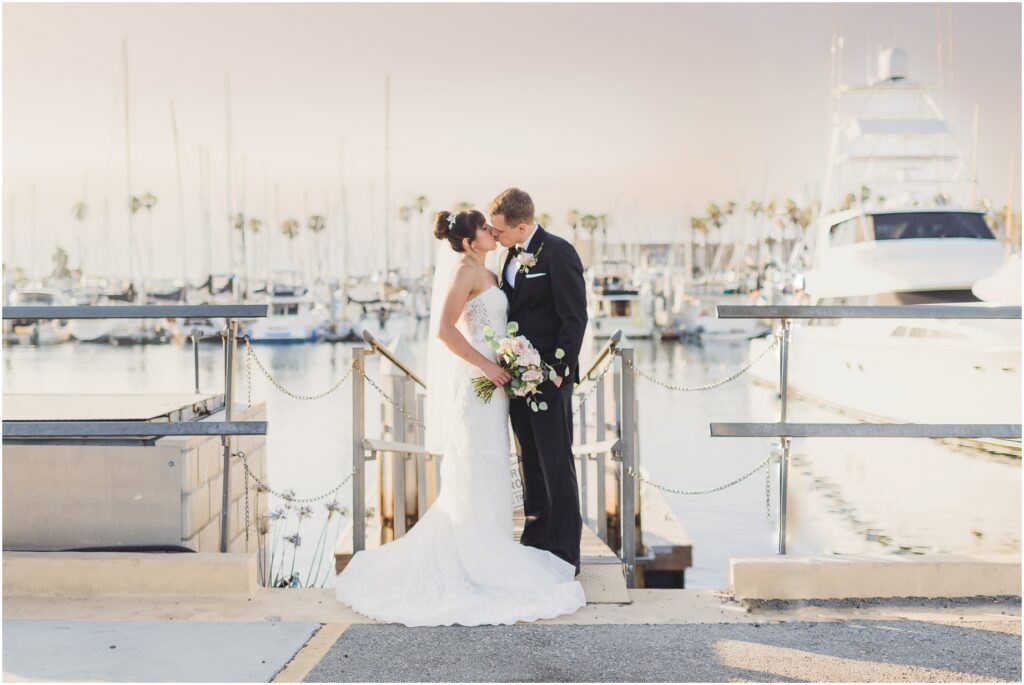 A bride and Groom kiss in front of the water at their wedding at the Portofino Hotel