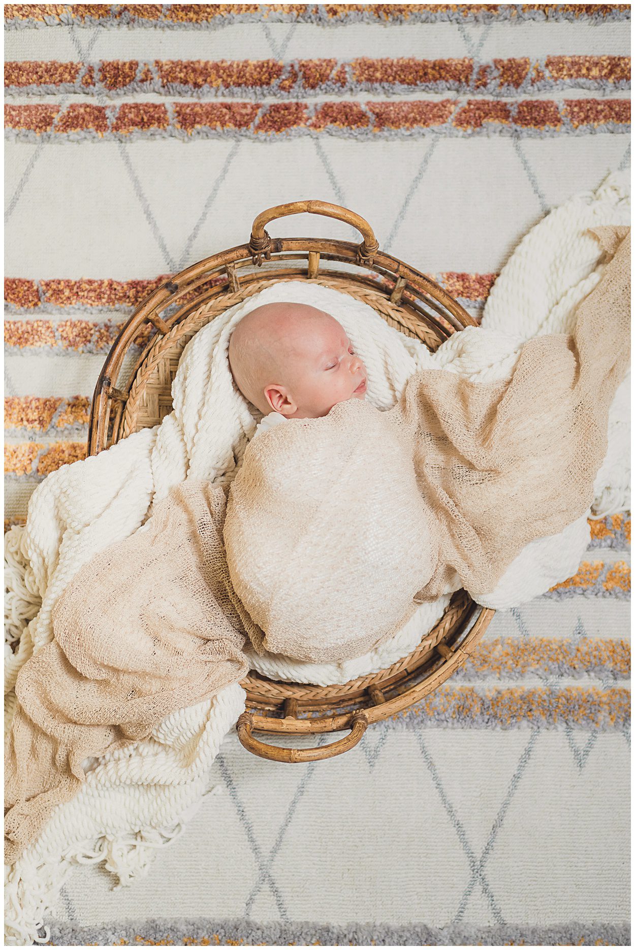 A newborn baby in a basket with blankets covering them during their in home newborn session in Portland Oregon