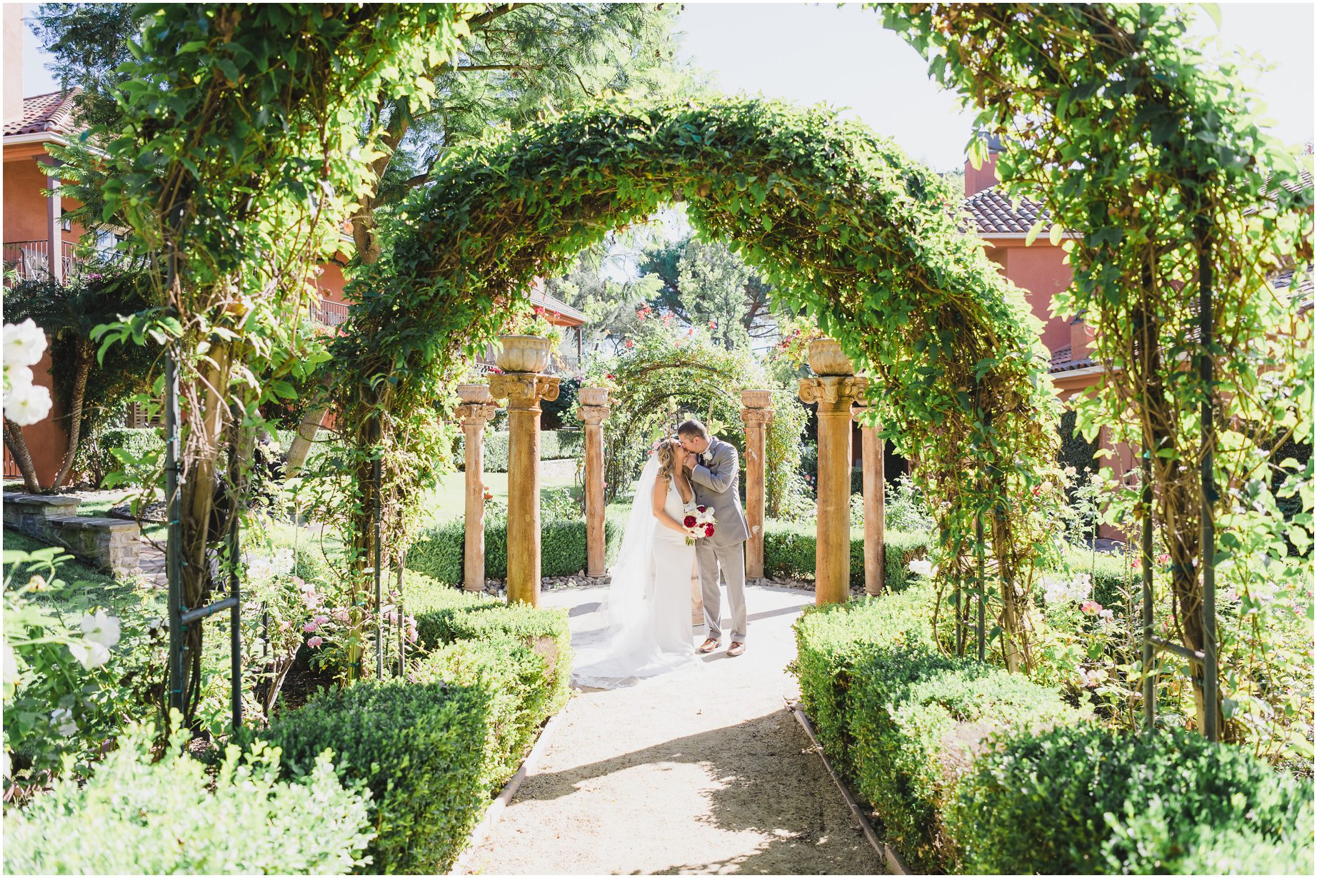 A bride and groom under arches of greenery at Westlake village in