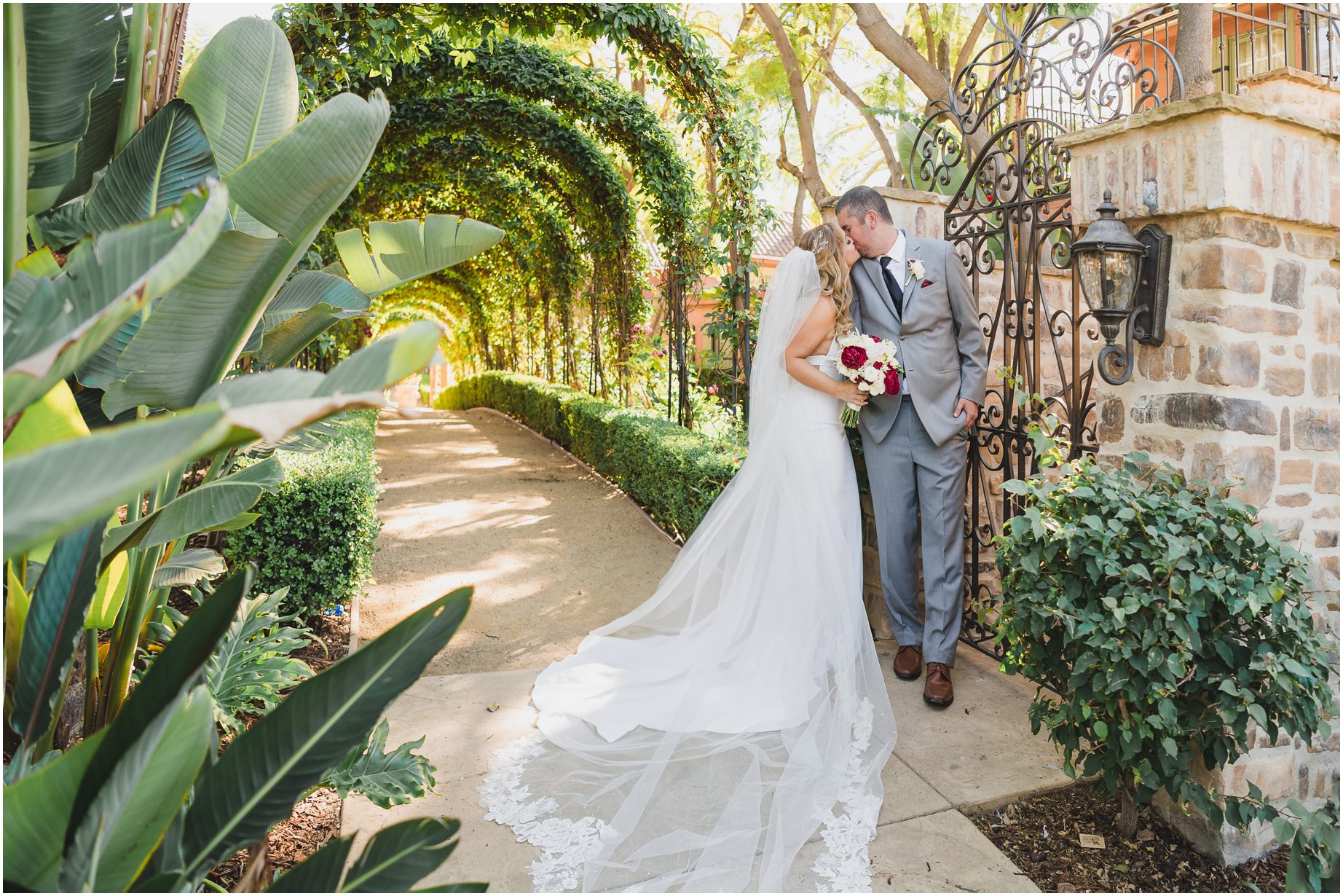 A bride and groom pose for couples portraits at Westlake village in, surrounded by tropical plants and a pillar
