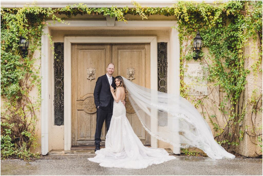 A bride and groom pose in front of double doors during their serendipity gardens wedding