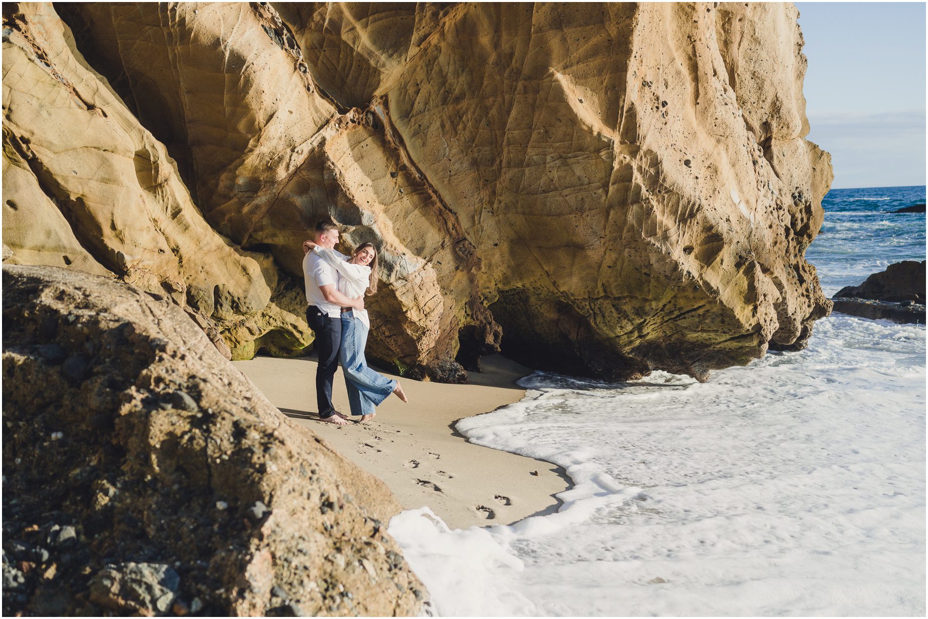 A couple watches the waves come in during their engagement session with Sun & Sparrow in Laguna Beach