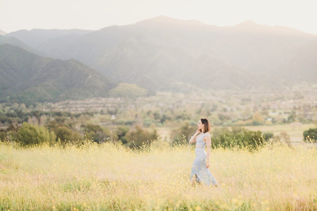 Ellie Fuqua, owner of Sun and Sparrow Photography, in a field of flowers in front of the Sierra Nevada Mountains in Southern California