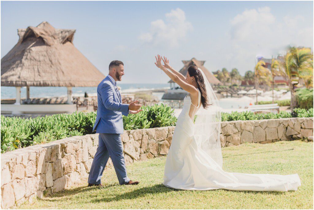 A bride and groom have their first look and she throws her arms up in excitement