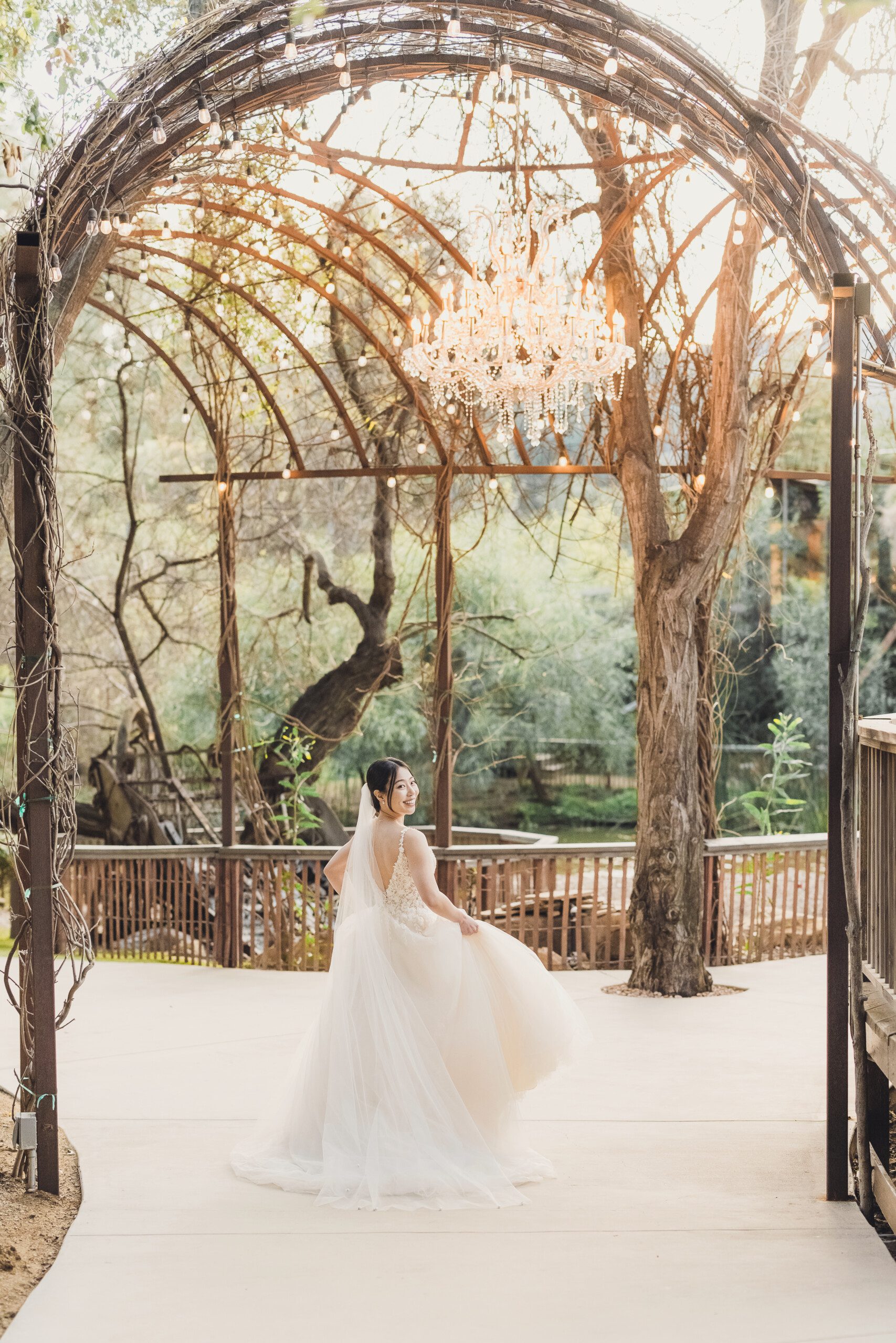 A bride stands under a chandelier arch at the Redwood Room in Malibu