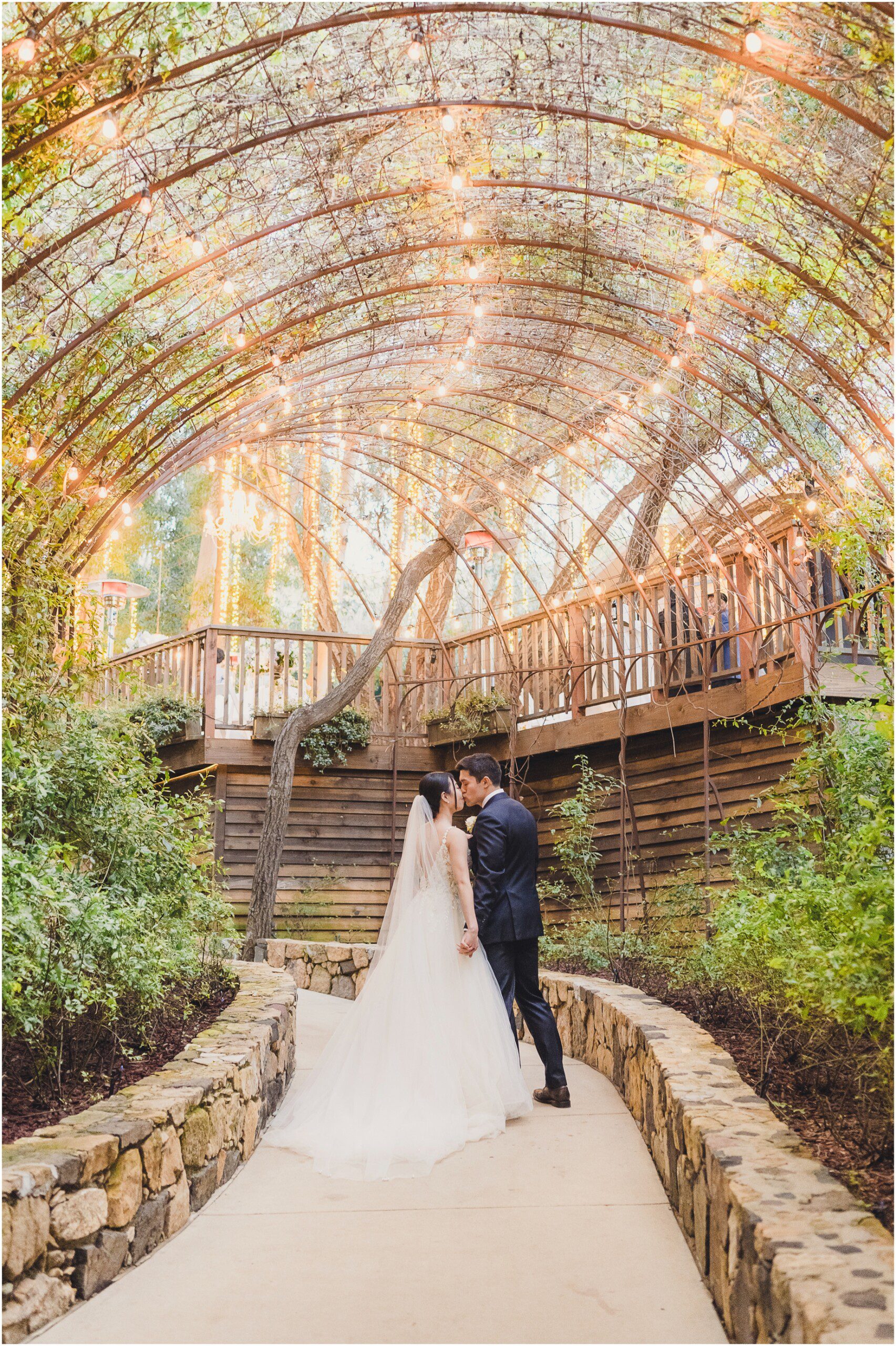 A bride and groom on a pathway with an ivy covered arch above it at the Calamigos Ranch Birchwood room