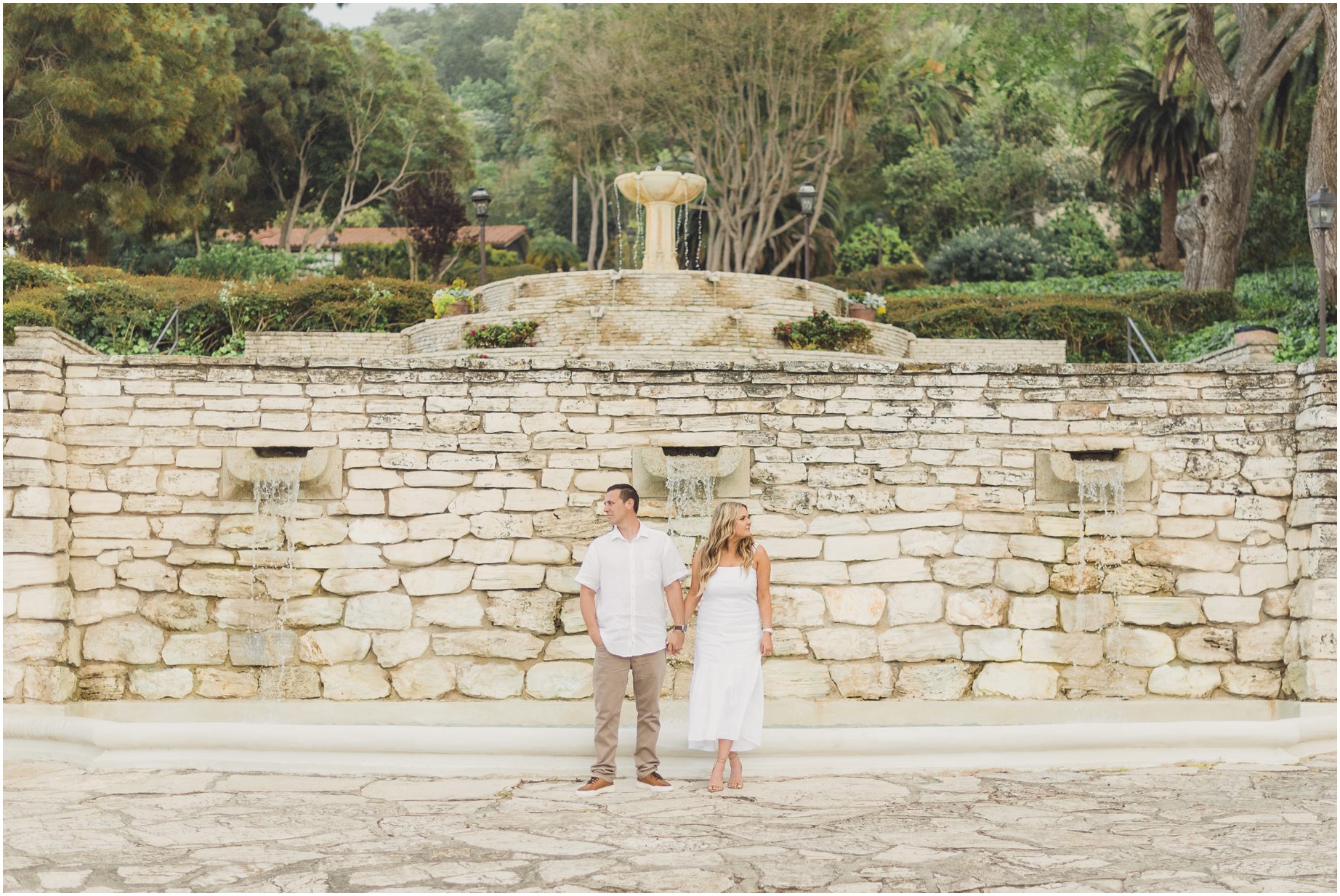 A couple stands in front of a stone water feature during their Palos Verdes Mini Session