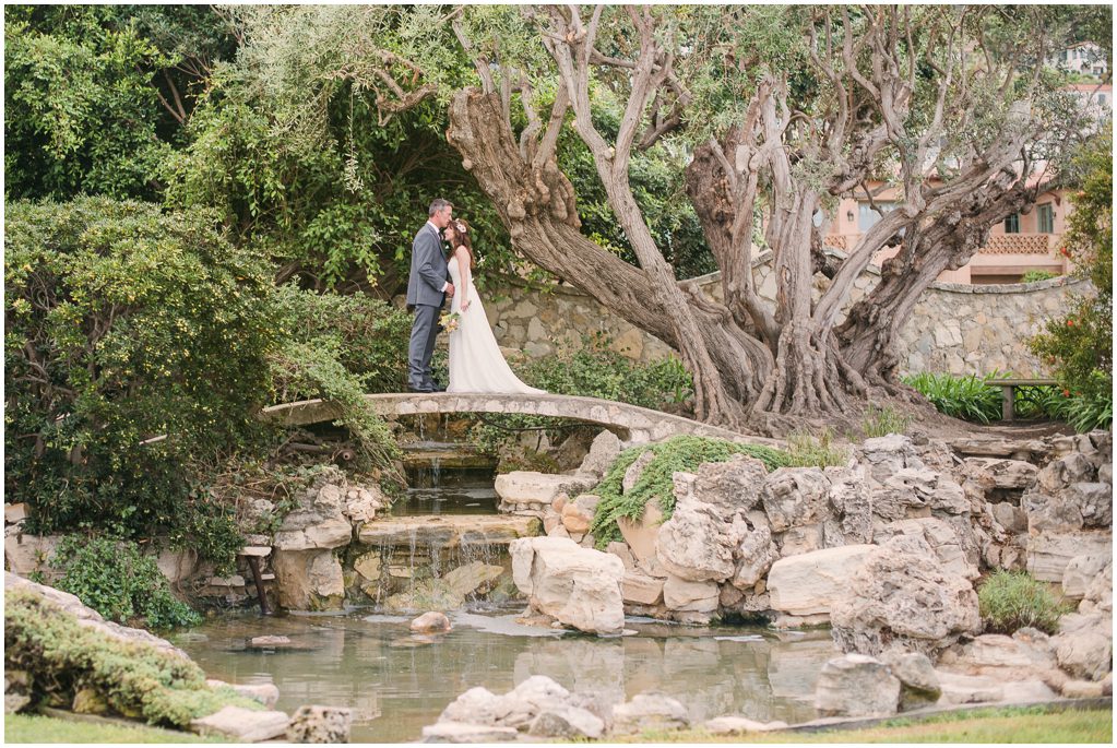 A bride and groom stand on a bridge at the Neighborhood Church