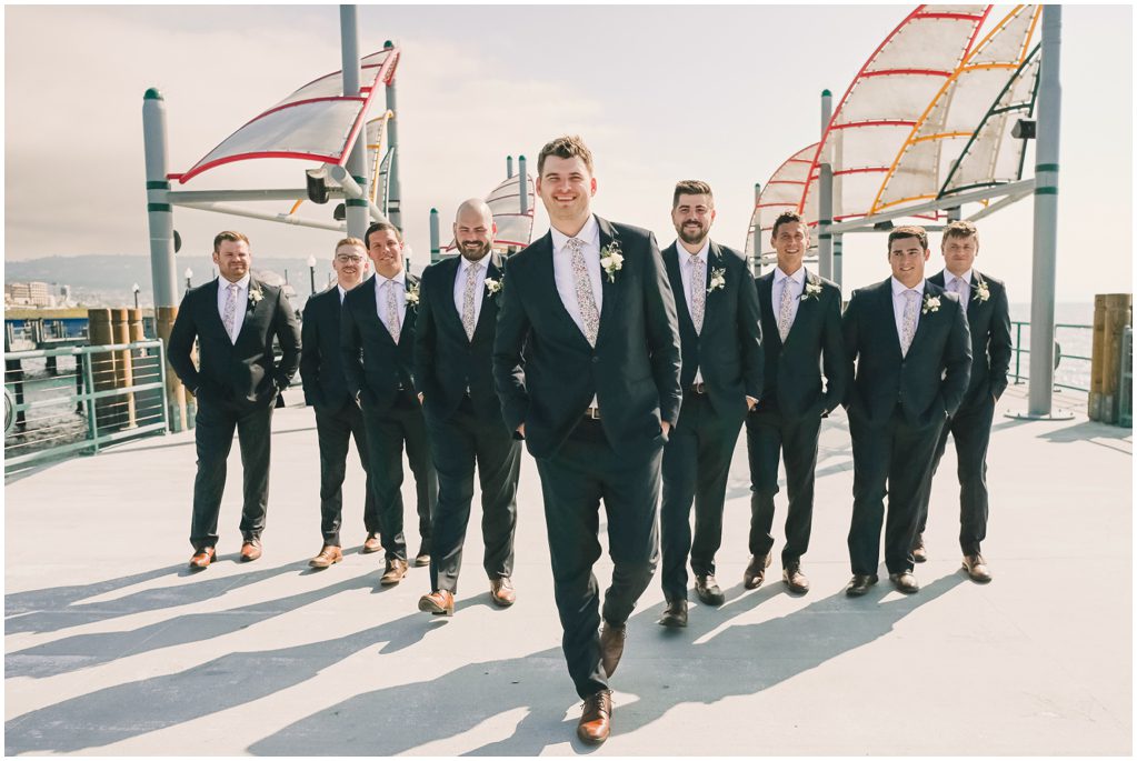 Groom and groomsmen walking in a V on Redondo Beach Pier
