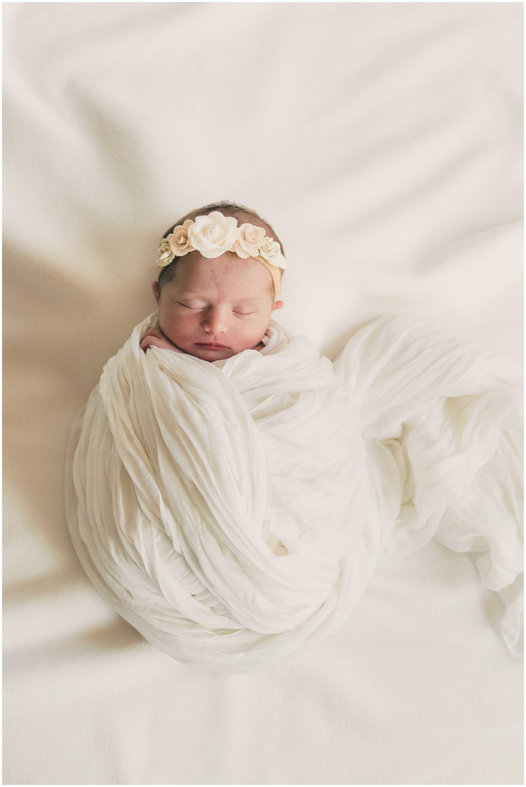 Baby wrapped in blanket laying on bed