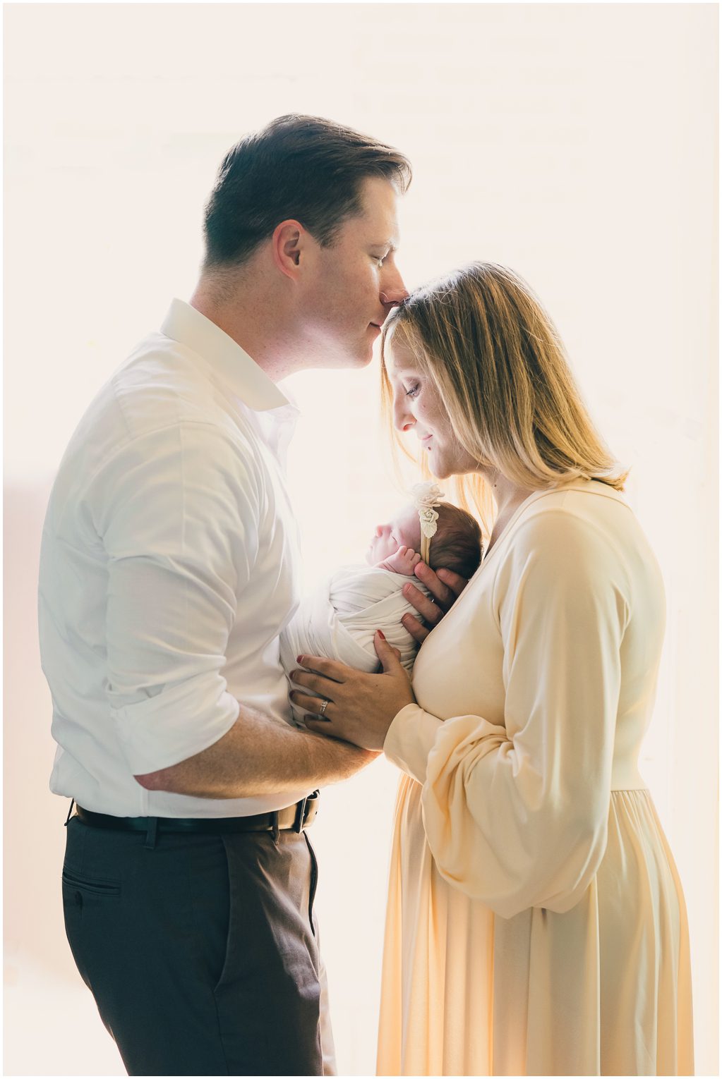 Mom and dad share an intimate moment while holding baby